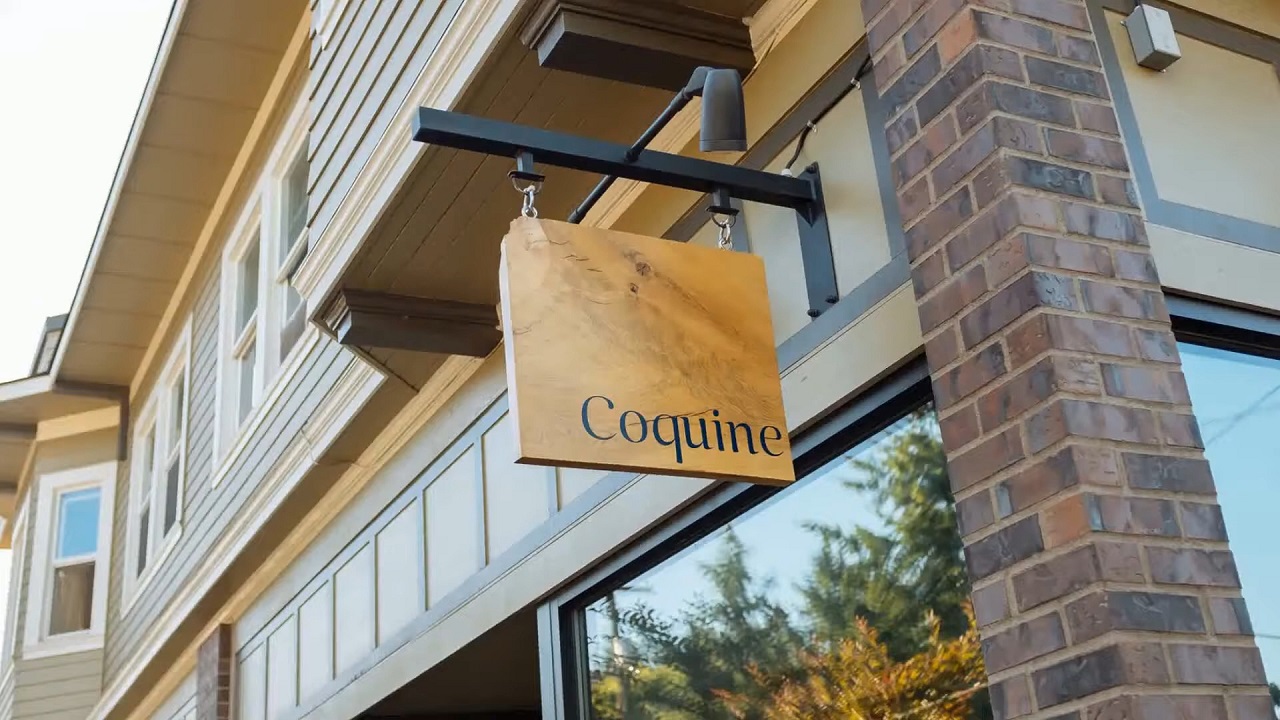 A rustic wooden sign outside Coquine, signaling a culinary adventure with farm-to-table inspirations