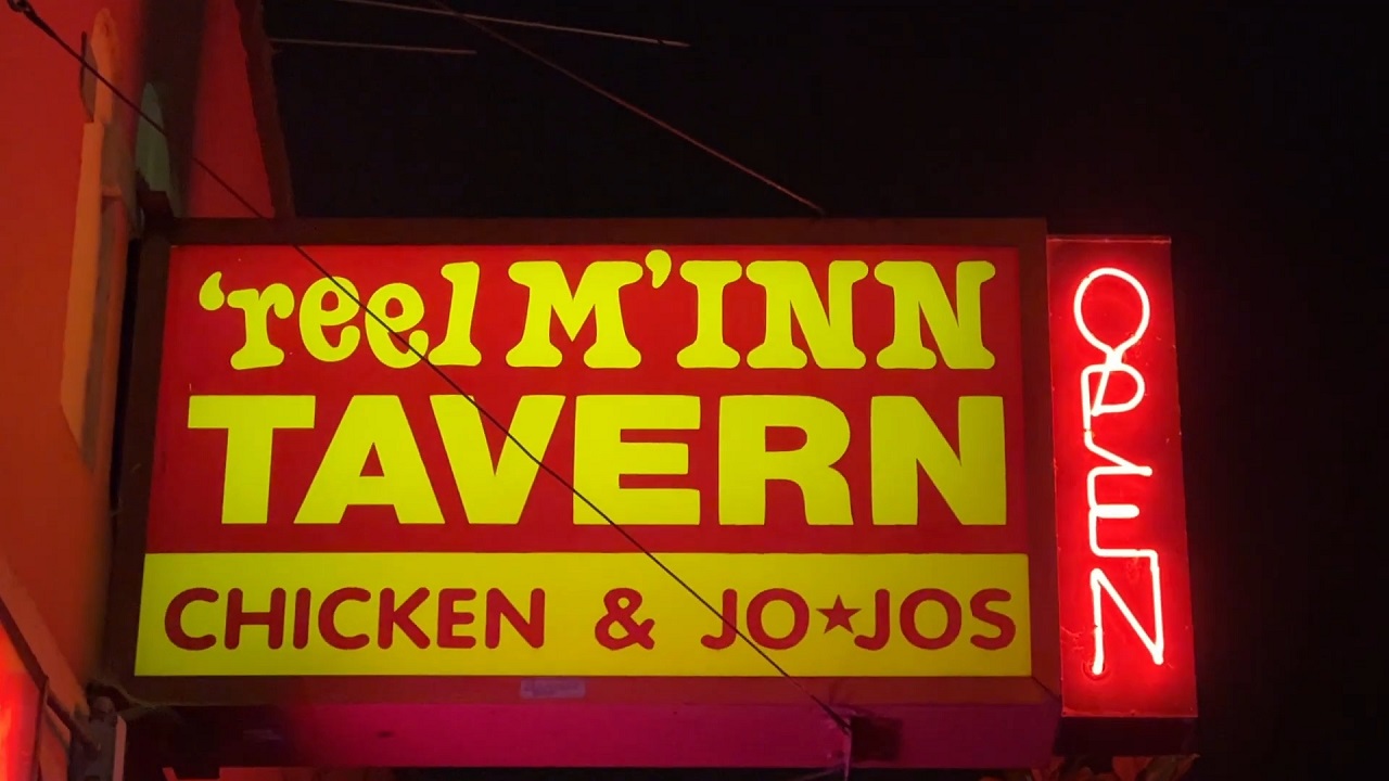 The vibrant neon signage of Reel M Inn Tavern, offering a retro vibe and delicious chicken and jo-jos